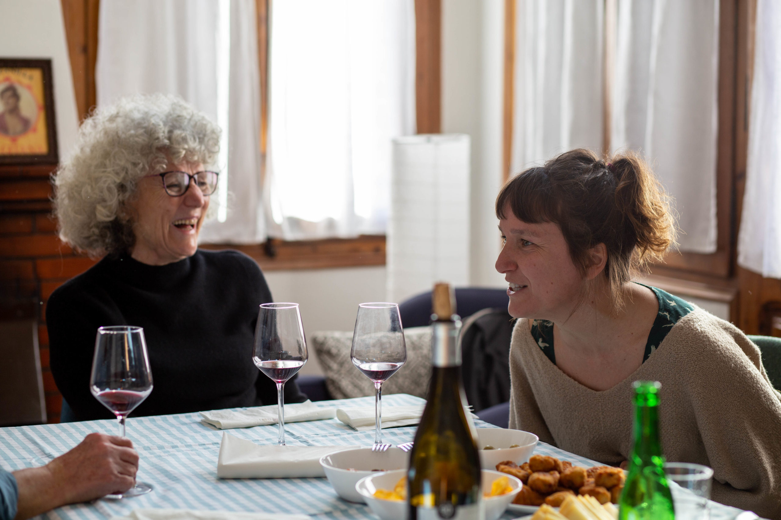 Dues dones rient en un dinar en un menjador de casa