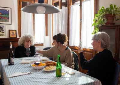 Tres amigues rient en un dinar en un menjador de casa