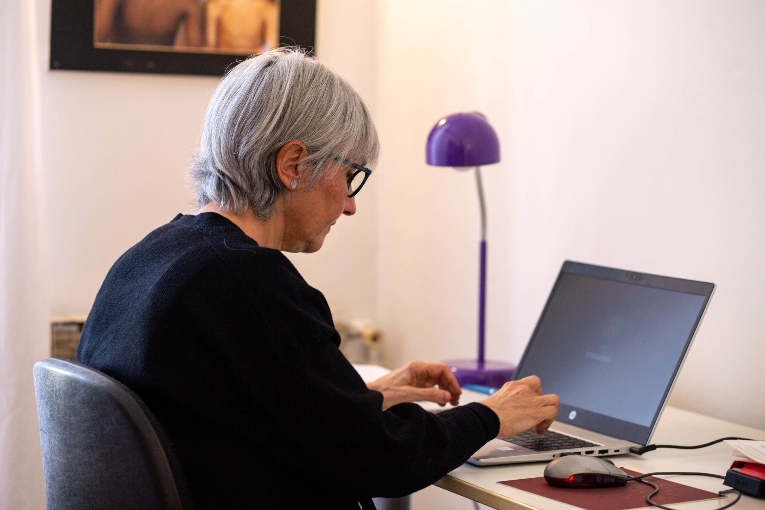 Dona asseguda escrivint a l'ordinador en un despatx