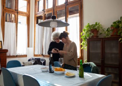 Vista general de dues dones mirant el mòbil al menjador de casa