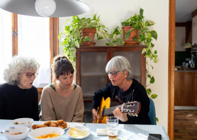 Tres amigues tocant la guitarra al menjador de casa