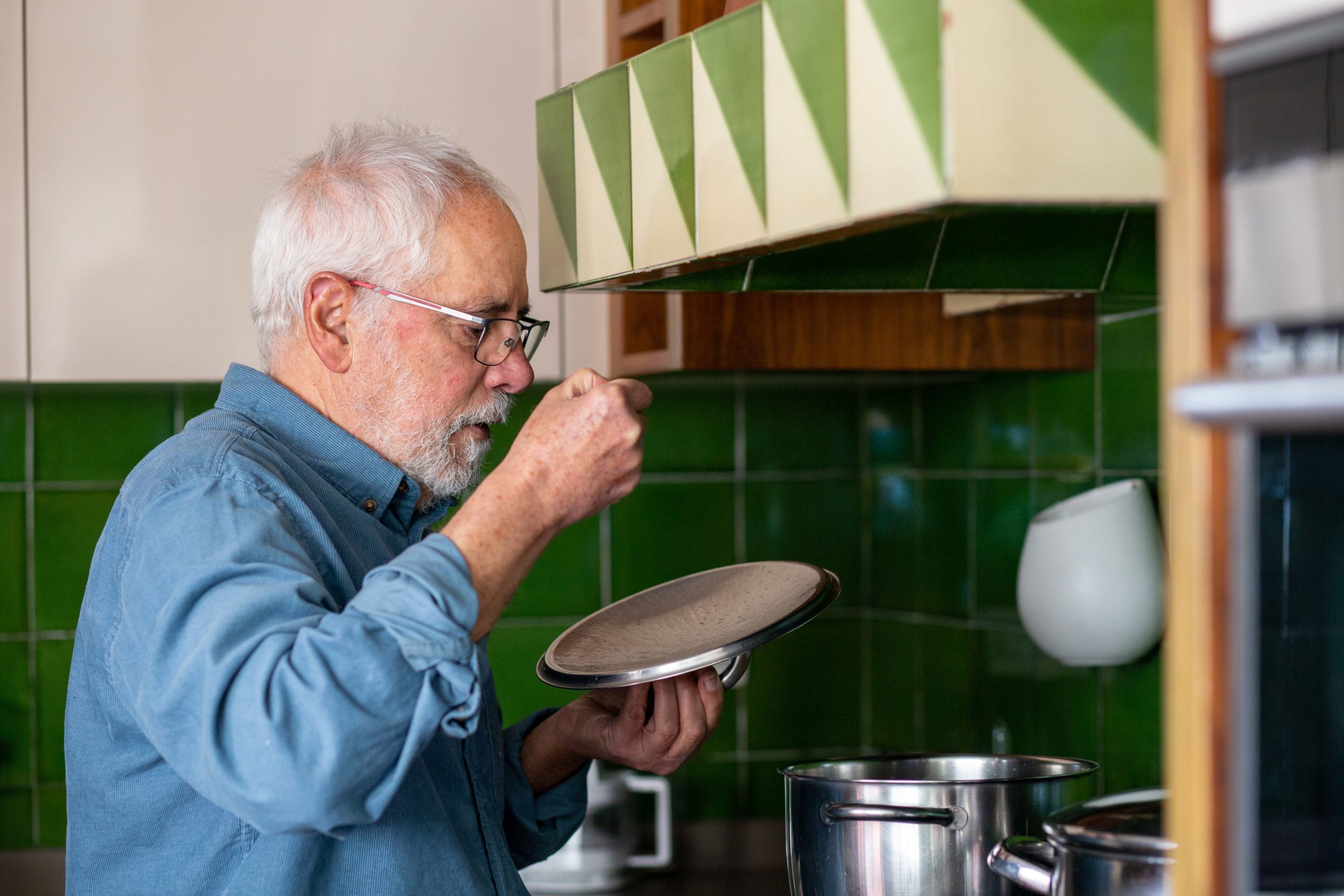 Home tastant el menjar d'una olla a la cuina