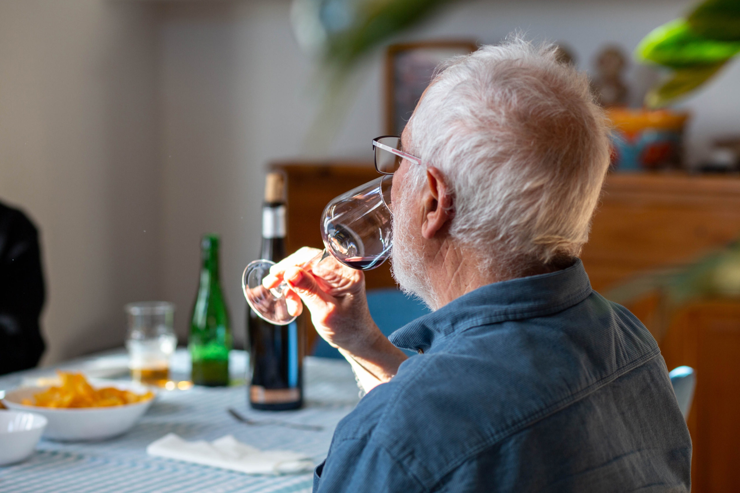Home prenent una copa de vi en un dinar al menjador de casa