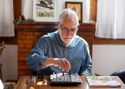 Home assegut al menjador de casa jugant als escacs