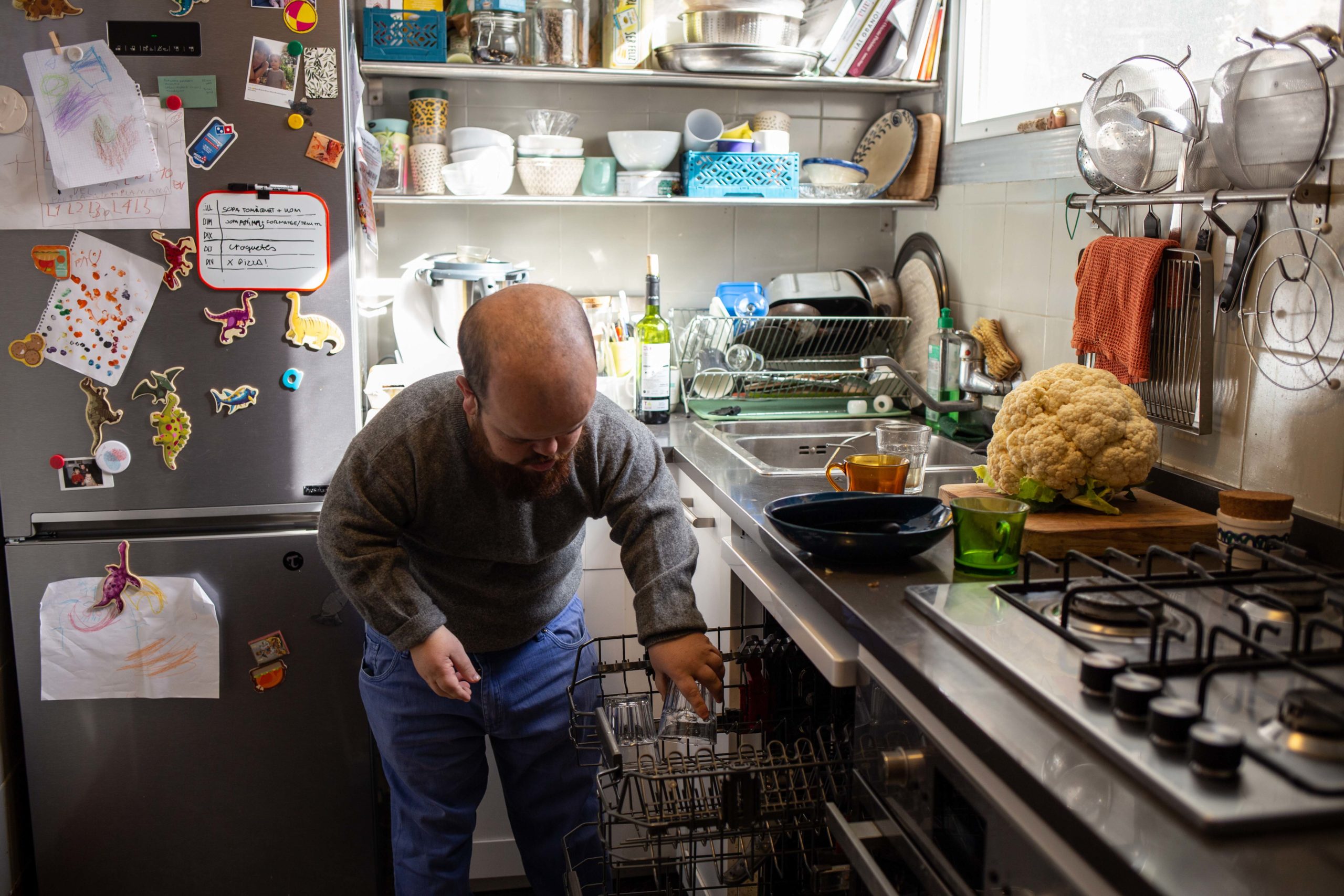 Un noi posa els plats dins del rentavaixelles a la cuina