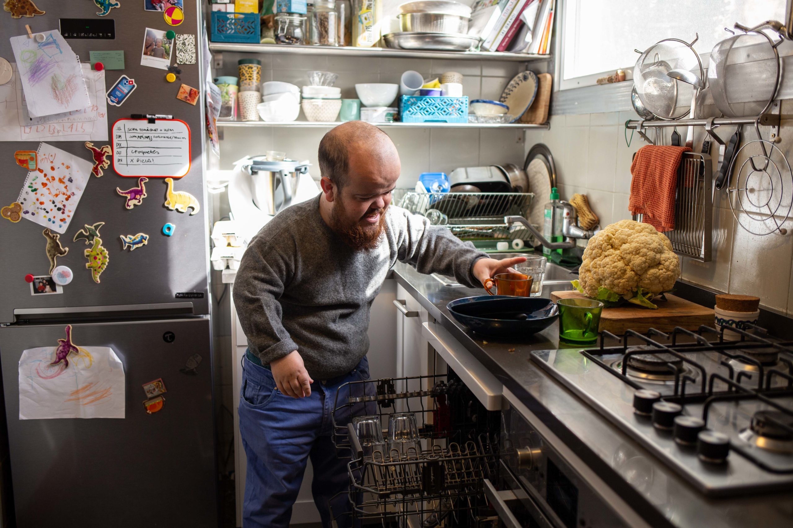 Un noi posa els plats dins del rentavaixelles a la cuina