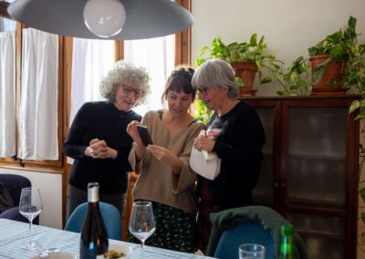 Tres dones mirant el mòbil al menjador de casa